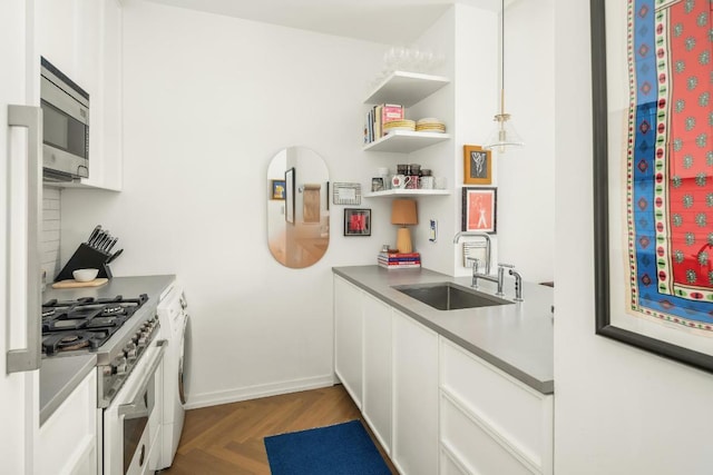 kitchen with sink, white cabinetry, appliances with stainless steel finishes, and dark parquet flooring