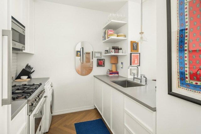 kitchen with stainless steel appliances, sink, dark parquet floors, and white cabinets