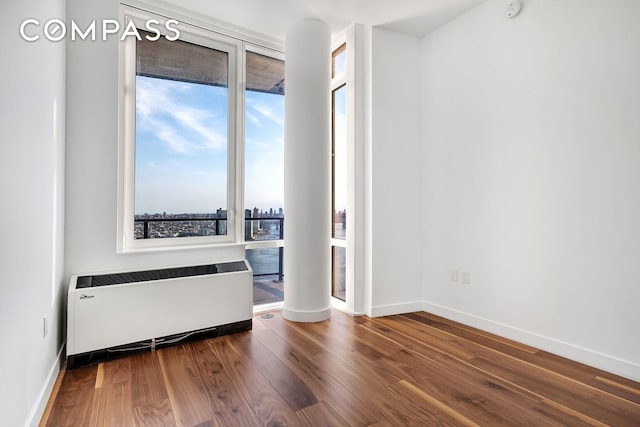 empty room featuring radiator, baseboards, and wood finished floors