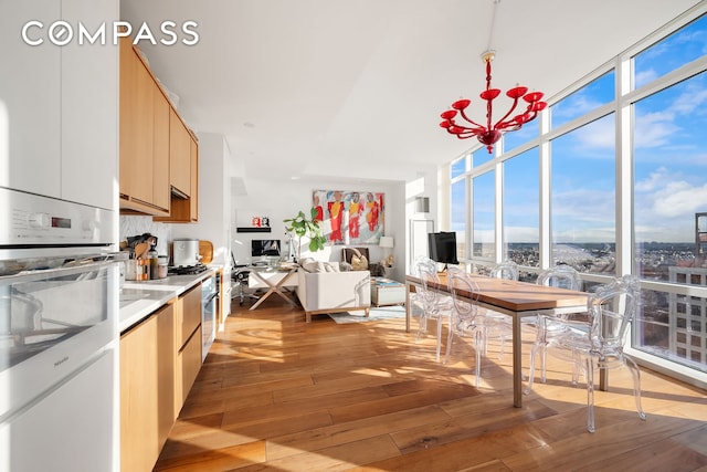 kitchen featuring a wall of windows, oven, light countertops, and light wood finished floors