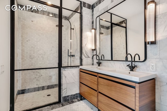 full bathroom with double vanity, a stall shower, a sink, and tile walls