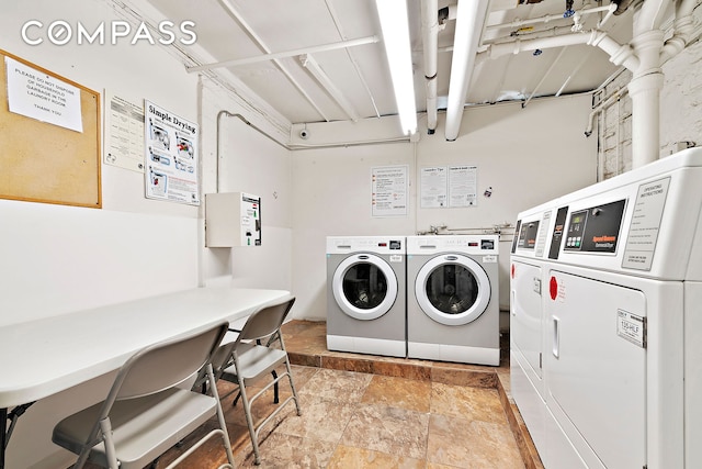common laundry area with separate washer and dryer and stone finish flooring