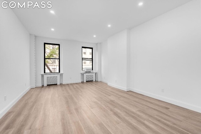 spare room with radiator heating unit and light wood-type flooring