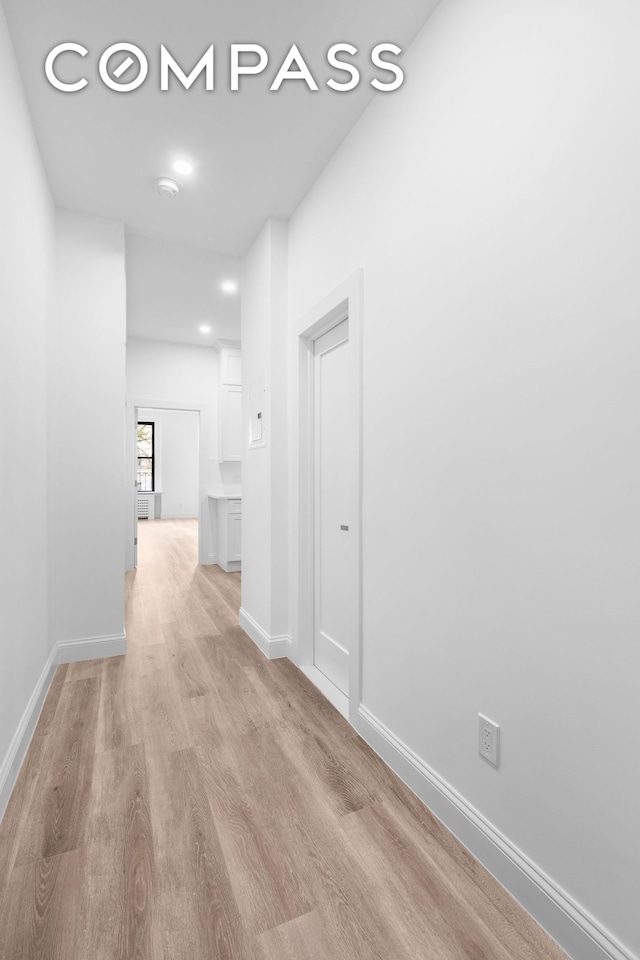 hall with light wood-style flooring and baseboards