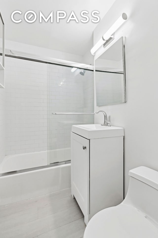 full bath with toilet, shower / bath combination with glass door, and vanity