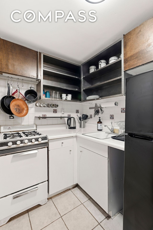 314 W 56th St Unit 4E, New York City, NY 10019 - kitchen featuring white gas stove, open shelves, freestanding refrigerator, and a sink