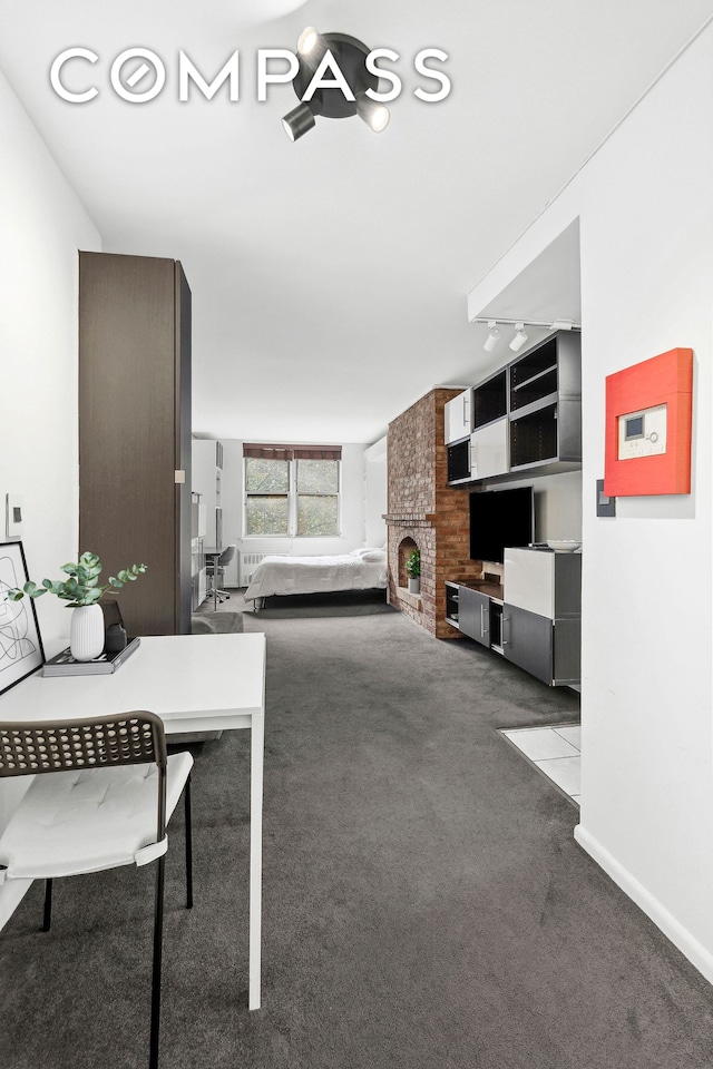 interior space featuring a brick fireplace, baseboards, and track lighting