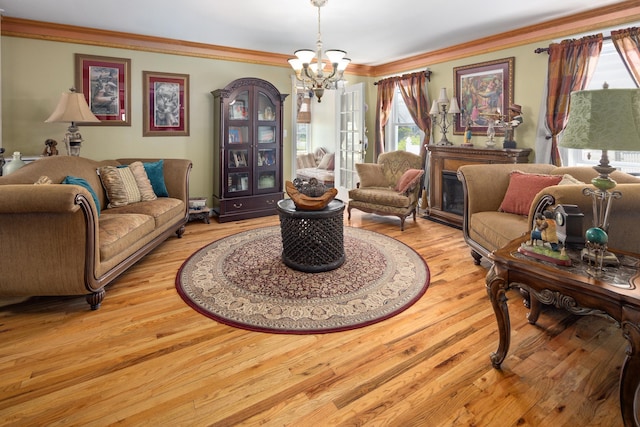 living room with crown molding, a notable chandelier, and light wood-style floors