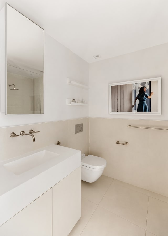 bathroom with tile patterned flooring, tile walls, toilet, and vanity