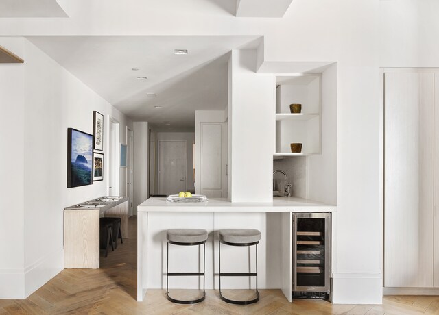 bar featuring a sink, wine cooler, backsplash, and wet bar