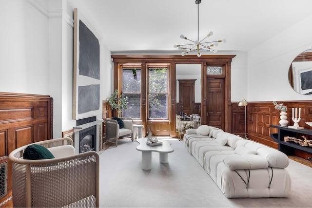 living area with a chandelier, a glass covered fireplace, and wainscoting