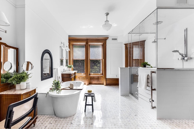 full bath with a stall shower, a freestanding tub, visible vents, and vanity