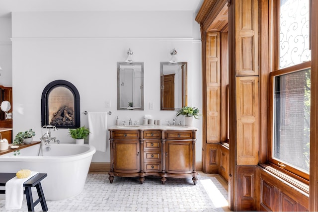 full bath with a sink, double vanity, tile patterned flooring, and a freestanding tub