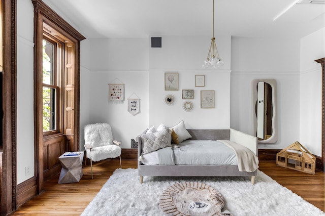 bedroom featuring visible vents, an inviting chandelier, and wood finished floors