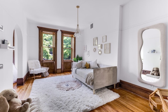 living room with arched walkways, wood finished floors, visible vents, and baseboards