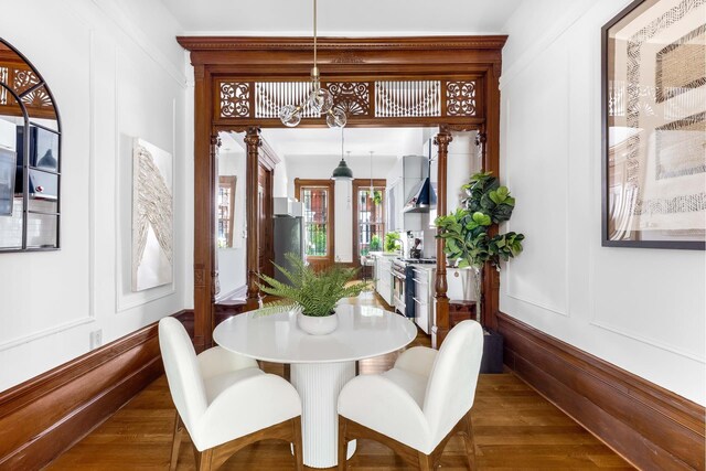 dining space featuring a decorative wall and dark wood finished floors