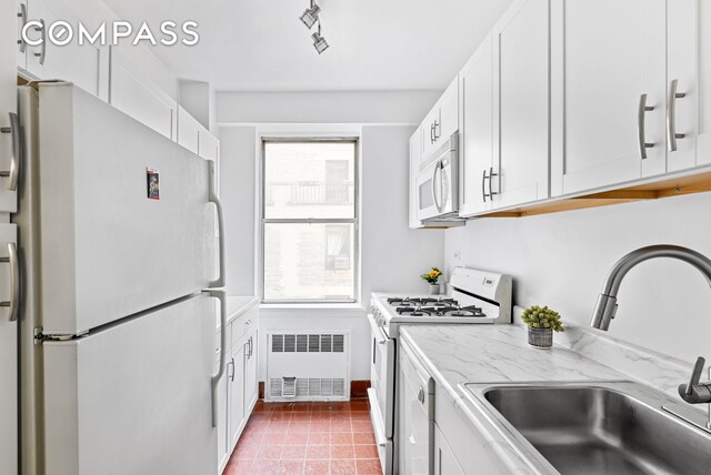 kitchen with white cabinetry, sink, radiator, and white appliances