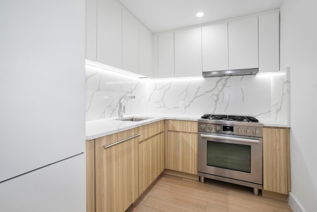 kitchen with freestanding refrigerator, stainless steel range with gas stovetop, modern cabinets, and white cabinetry