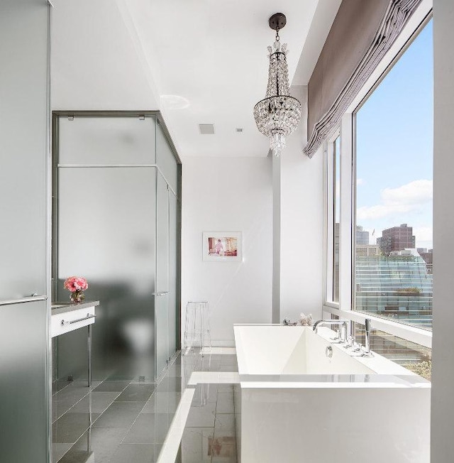 bathroom with a soaking tub, a view of city, visible vents, and a notable chandelier