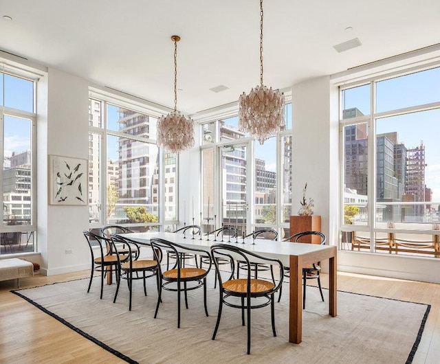 dining room featuring a chandelier, a wealth of natural light, a city view, and light wood finished floors