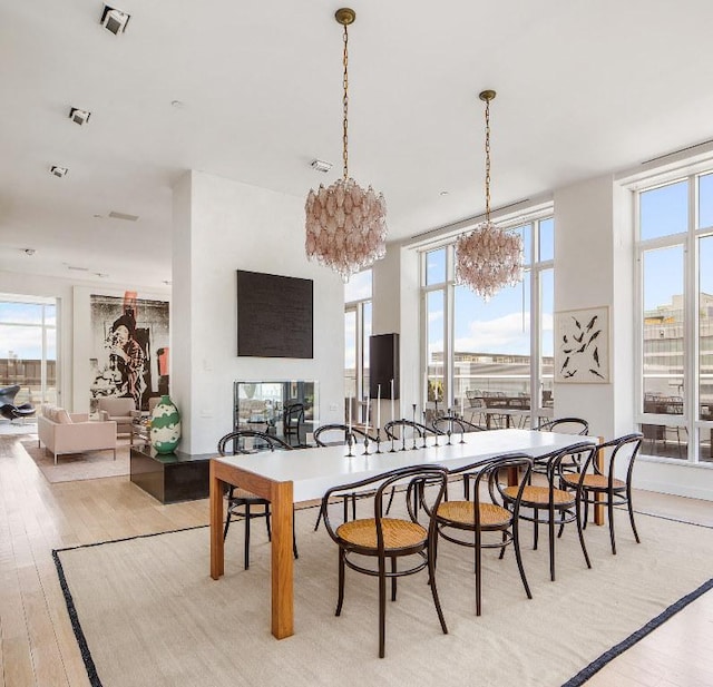 dining room with light wood-type flooring, a healthy amount of sunlight, visible vents, and a chandelier