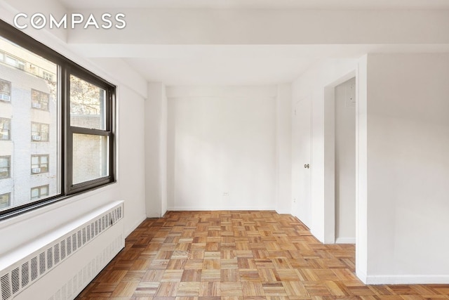 empty room featuring radiator heating unit and baseboards