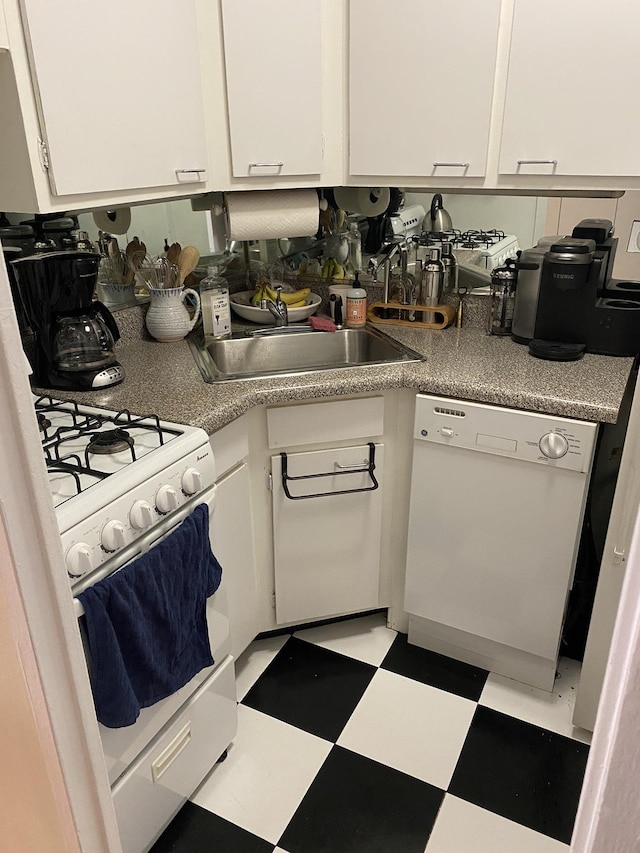 kitchen with white appliances, a sink, white cabinetry, light countertops, and light floors