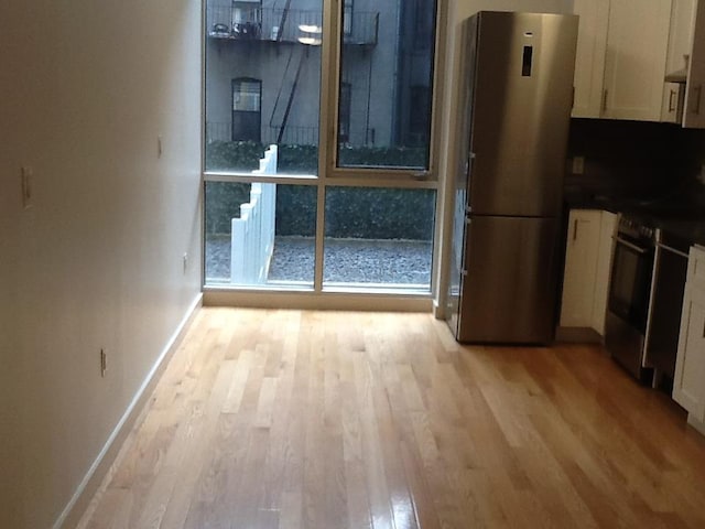 interior space featuring white cabinets, light wood-type flooring, and stainless steel fridge