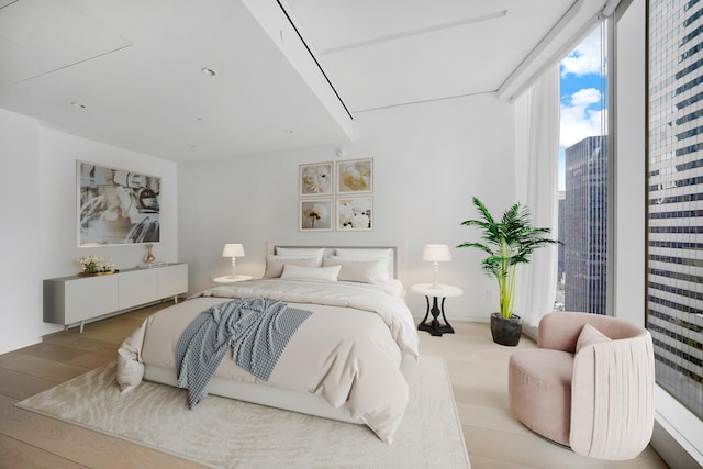 bedroom with a view of city and wood finished floors