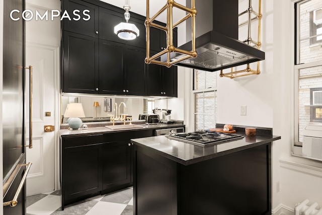 kitchen with range hood, dark cabinetry, a sink, and dark countertops