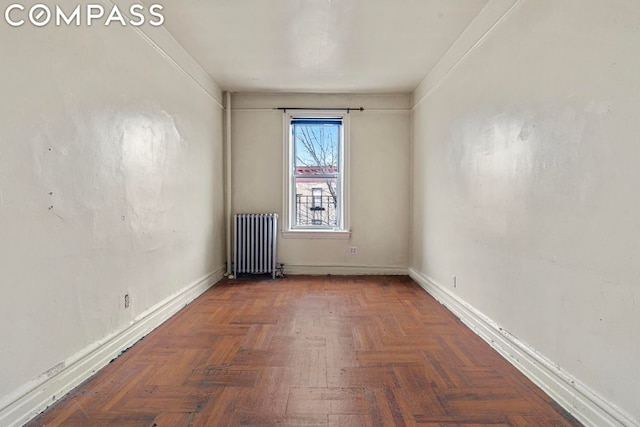 empty room featuring radiator, ornamental molding, and dark parquet floors