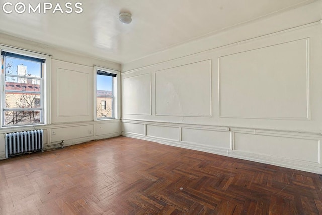 unfurnished room featuring radiator and dark parquet floors