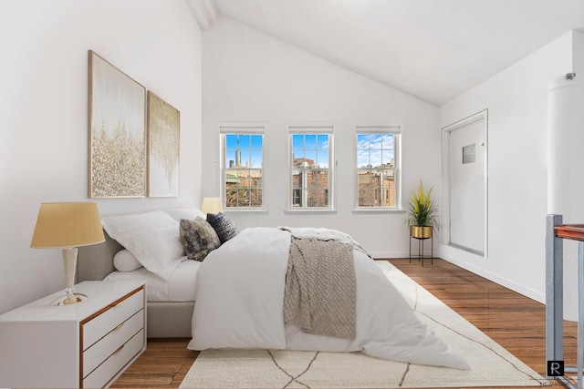 bedroom featuring high vaulted ceiling, baseboards, and wood finished floors