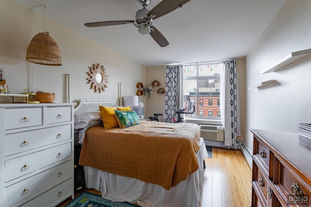 bedroom featuring light wood-style floors, a baseboard radiator, a wall mounted air conditioner, and a ceiling fan