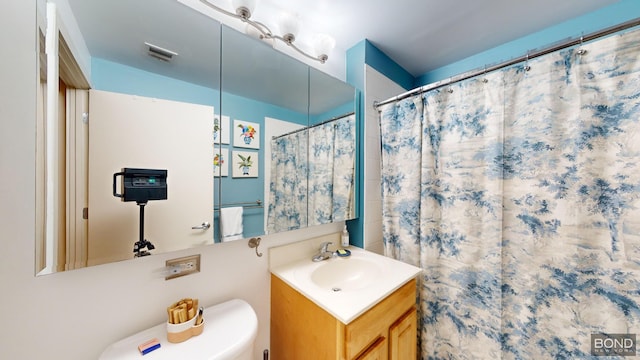 bathroom featuring a shower with shower curtain, visible vents, vanity, and toilet