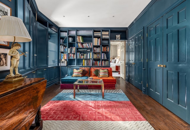 sitting room with ornamental molding, dark wood-type flooring, and built in shelves