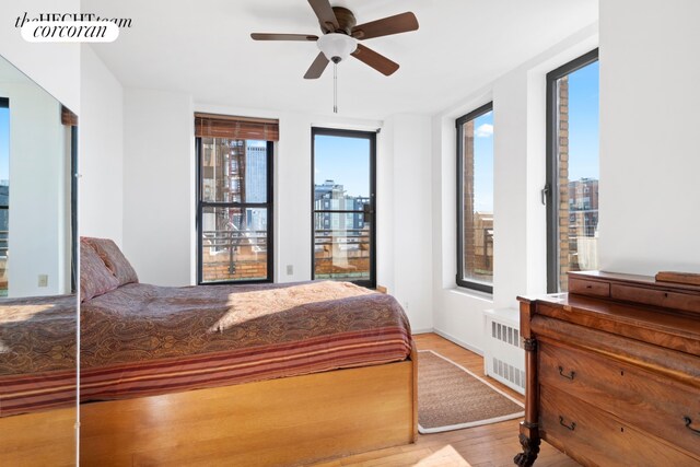 bedroom featuring ceiling fan, radiator, multiple windows, and light wood-type flooring