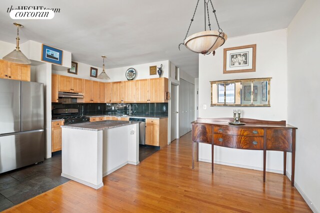 kitchen with hanging light fixtures, backsplash, hardwood / wood-style floors, stainless steel appliances, and a kitchen island