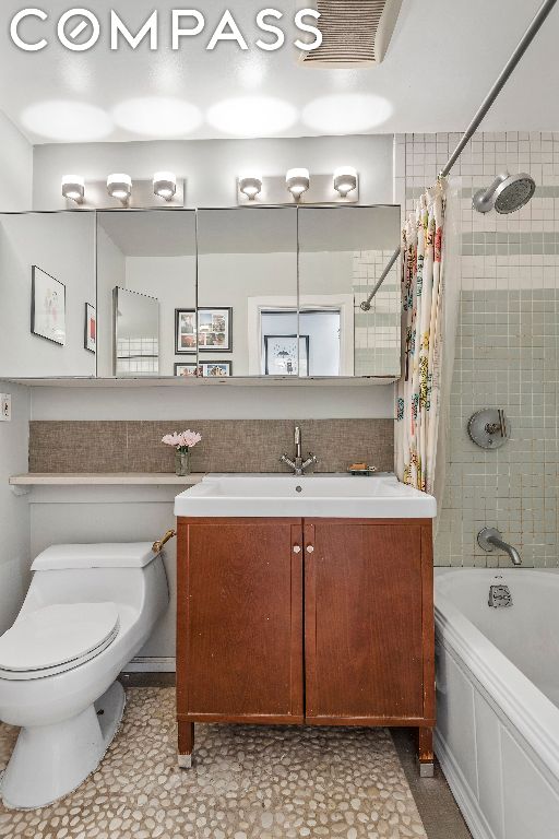 full bathroom featuring toilet, vanity, and shower / tub combo with curtain