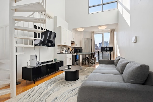 living room with light hardwood / wood-style floors and a high ceiling