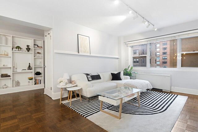 living room featuring radiator, dark parquet flooring, and rail lighting