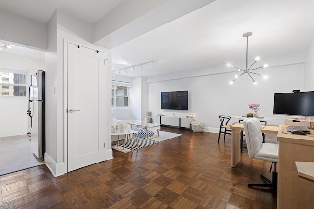 office area with track lighting, dark parquet flooring, and a notable chandelier