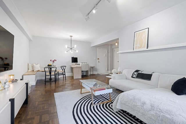 living room with an inviting chandelier, rail lighting, and dark parquet floors