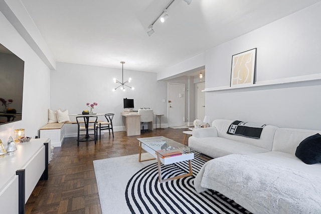 living room featuring a chandelier, track lighting, and baseboards