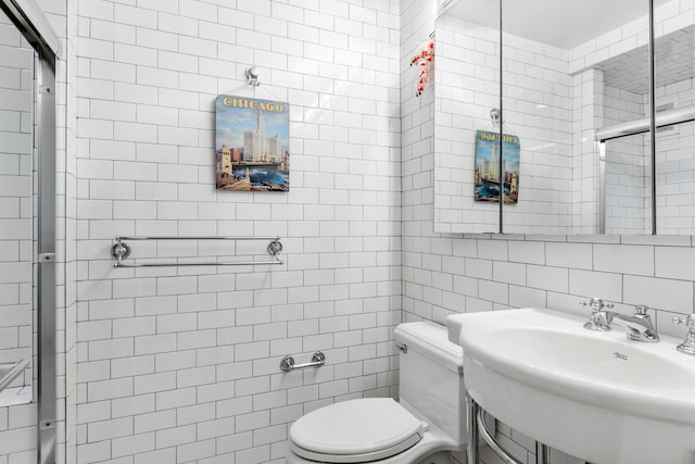 bathroom featuring tile walls, toilet, and a sink