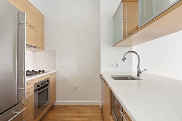 85 Adams St Unit 15-B, New York City, NY 11201 - kitchen with appliances with stainless steel finishes, a sink, light wood finished floors, baseboards, and light brown cabinetry