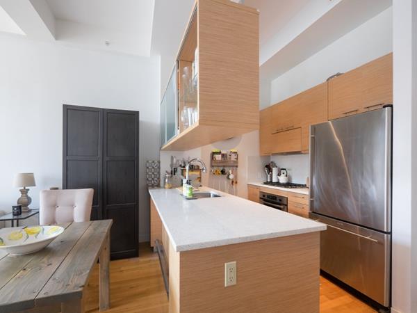 kitchen featuring light wood finished floors, stainless steel appliances, light countertops, a high ceiling, and a sink