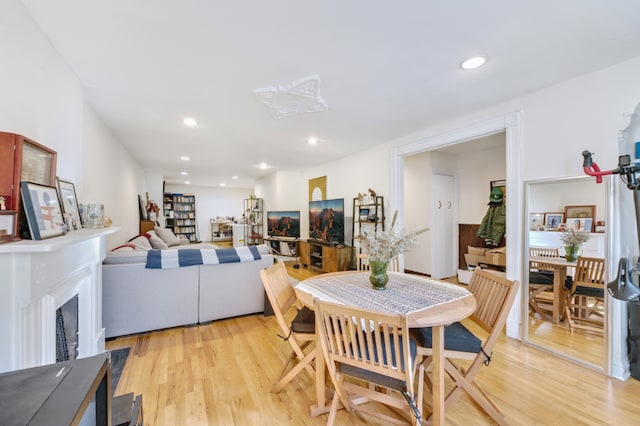 dining area featuring a fireplace, light wood-style flooring, and recessed lighting