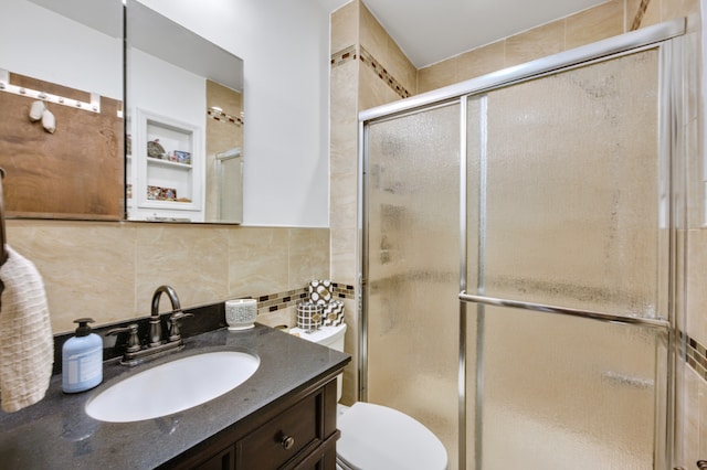 bathroom featuring toilet, vanity, tile walls, decorative backsplash, and a stall shower