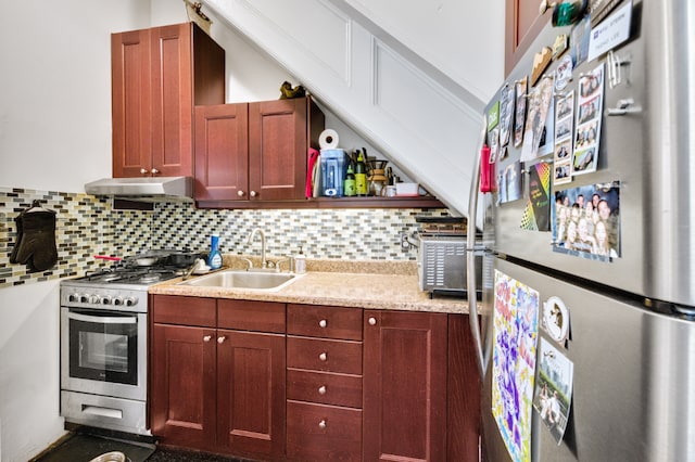 kitchen with under cabinet range hood, stainless steel appliances, a sink, light countertops, and tasteful backsplash